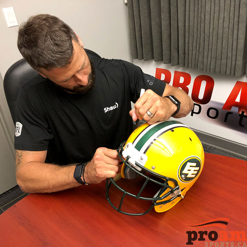 Edmonton Football Team player Mike Reilly signing a yellow  Edmonton Elks helmet during a private signing at Pro Am Sports in Edmonton