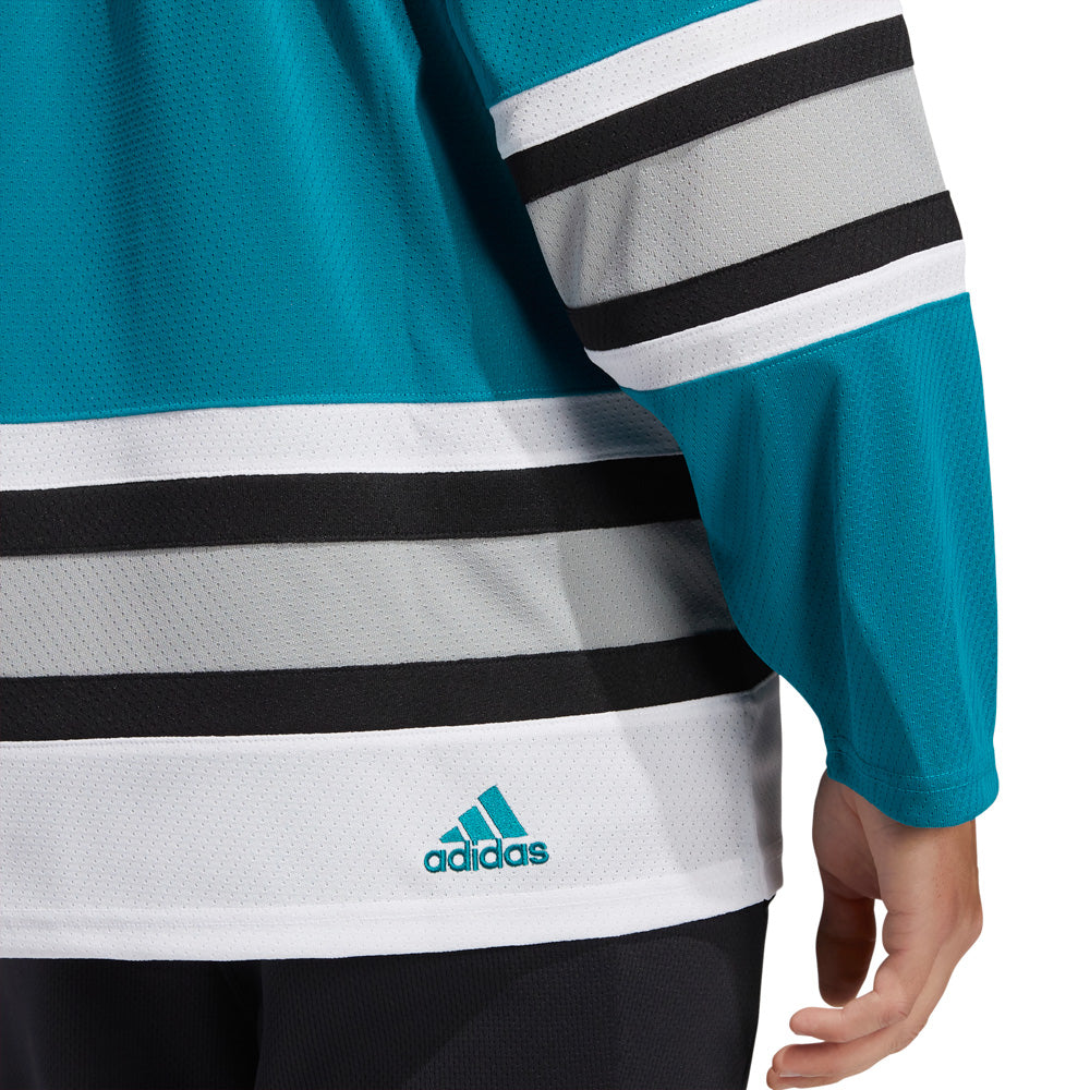 Detail view of adidas vintage team classics 1991 San Jose Sharks jersey, featuring a small embroidered adidas logo at the bottom hem on the right side.