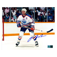 Photo of Edmonton Oiler Mark Messier looking down the rink during an Edmonton Oilers NHL hockey game, wearing white jersey. Photo is signed in the lower right with blue ink.