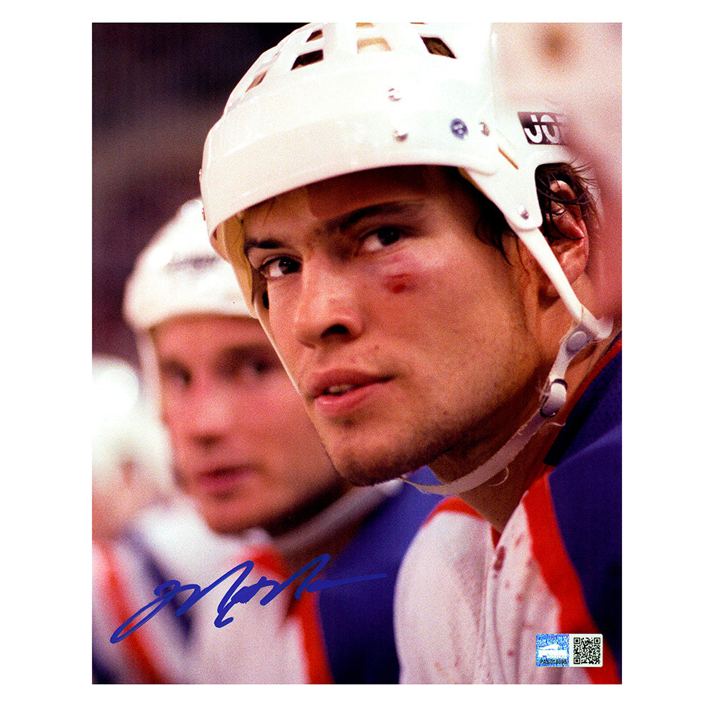 Signed photo of young Edmonton Oilers Mark Messier sitting on the bench during and Oilers game. He is wearing his helmet and has bruising and a cut on his eye and a bandaid over his eyebrow. He is looking slightly above and beyond the camera. The photo is signed in the lower left corner in blue ink.
