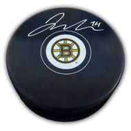 Black NHL hockey puck with Boston Bruins logo, puck has been signed by Jake Debrusk with silver ink.