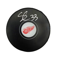 Black NHL hockey puck with Detroit Red Wings Logo, puck is signed by Sebastian Cossa.