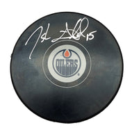 Black NHL hockey puck with Edmonton Oilers logo; puck is signed by Josh Archibald.