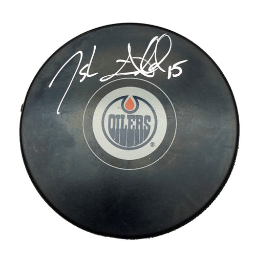 Black NHL hockey puck with Edmonton Oilers logo; puck is signed by Josh Archibald. 