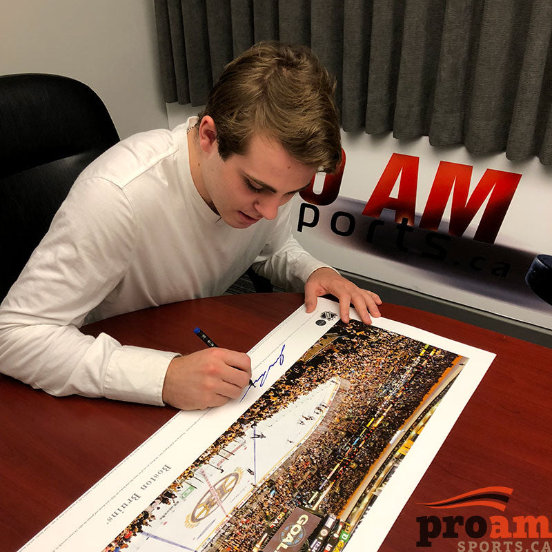 Jake DeBrusk signing a large panoramic photo of a Boston Bruins game during a private signing at Pro Am Sports in Edmonton