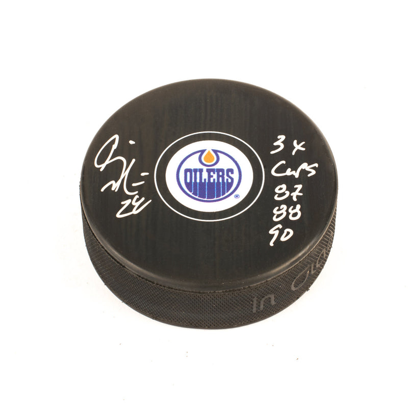 Black NHL hockey puck with Edmonton Oilers logo. Signed by Craig Muni with "3x Cups 87, 88, 90" Inscription