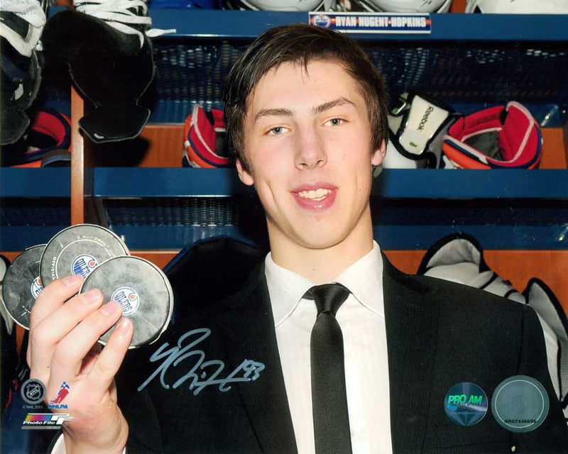 Signed photo of Ryan Nugent-Hopkins holding black pucks with Oilers logo from his first NHL  hat trick 