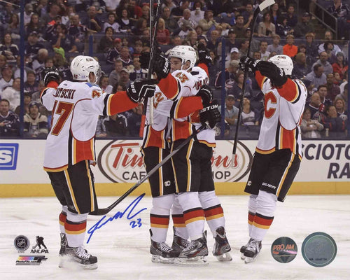Sean Monahan celebrating with his Calgary Flames teammates on ice after his first NHL goal. Image is signed in blue ink by Monahan. 