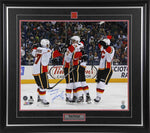Sean Monahan and teammates celebrating on ice after his first NHL goal with the Calgary Flames. Photo is signed by Monahan in blue in with the inscription "1st NHL Goal". Photo is shown framed with black frame, black mat with red accents, and inset Calgary Flames team pin and descriptive plate. 