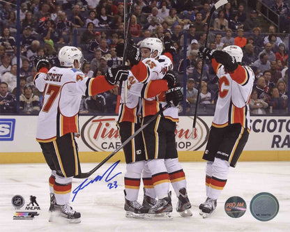 Autographed 8x10 photo of Sean Monahan in a Calgary Flames uniform, celebrating a goal, with a group of teammates in the background. The photo comes with a signature and is framed.