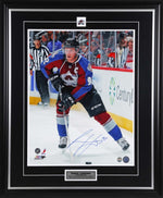 Gabriel Landeskog skating during a Colorado Avalanche NHL hockey game. He is wearing red and blue team jersey with captain's "C". Photo is signed by Landeskog with blue ink. Photo is shown framed, with black frame, black mat with silver accents, and inset team pin and description bar. 