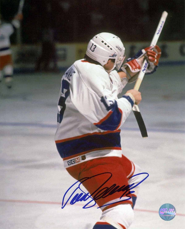 Teemu Selanne celebrating his Rookie Goal Record during a Winnipeg Jets NHL game. He is facing away from the camera and is wearing the Jets' white jersey. The photo is signed by Selanne in blue ink in the bottom centre. 