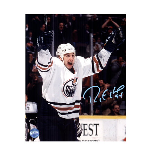 Photo of Edmonton Oiler Ryan Smyth celebrating during an Edmonton Oilers NHL hockey game, he is wearing white jersey. Photo is signed with light blue ink on the right side. 