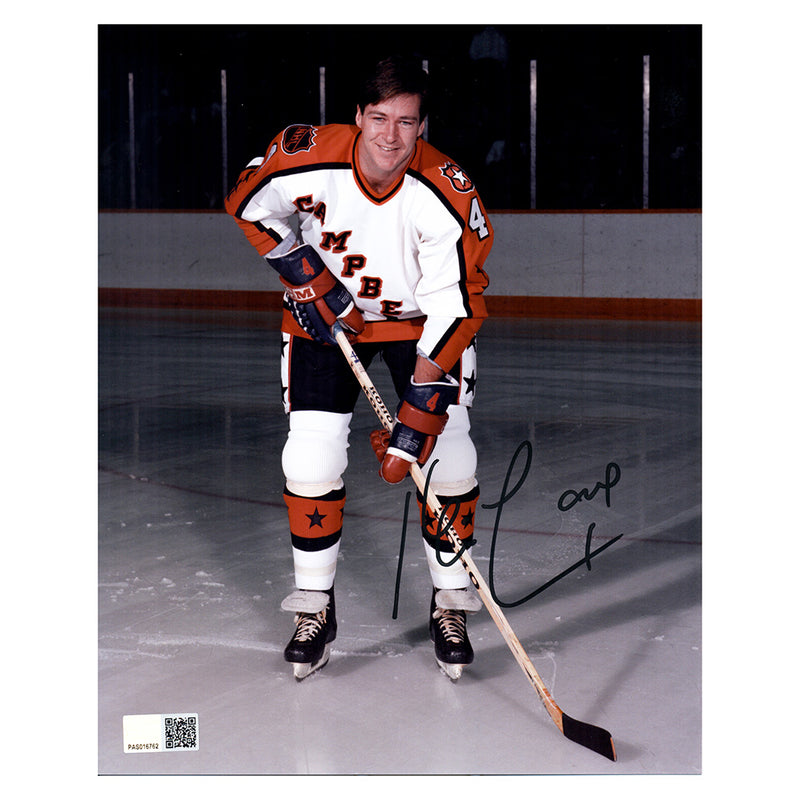 Kevin Lowe posed photo taken at the 1985 Campbell tournament. Lowe is wearing the orange, white and black Campbell jersey with NHL shield and stars. Photo is signed by Lowe in the lower right side of the photo.