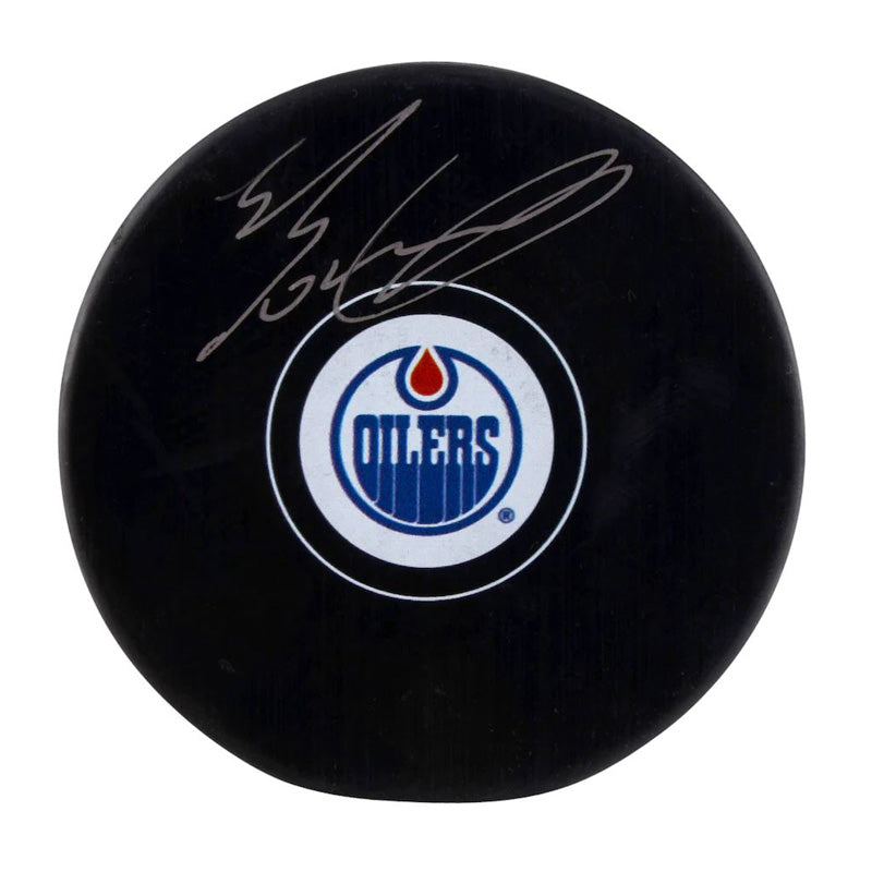 Black hockey puck with Edmonton Oilers logo, signed by Evan Bouchard in grey ink