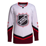 Front view of white and red 2022 NHL All-Star game jersey, featuring black and white NHL crest with red outline, two red stars on each sleeve, and red and black angled striping on sleeves and bottom hem. 