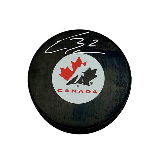 Black hockey puck with Team Canada logo on the front, signed in white by Ethan Bear 