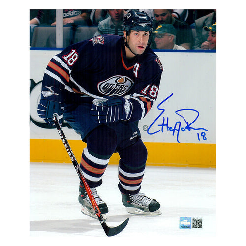 Signed photo of Ethan Moreau skating during an Edmonton Oilers NHL hockey game, wearing navy jersey with alternate captain's A. Photo is signed in blue in the centre right side of the image. 