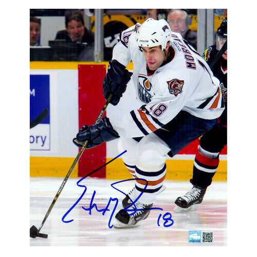 Signed photo of Ethan Moreau skating with puck during an Edmonton Oilers NHL hockey game wearing while Oilers jersey. Photo is signed in blue ink in the centre bottom of the photo. 