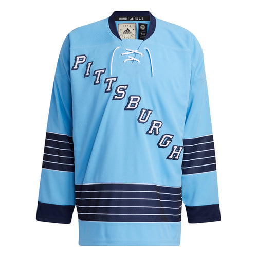 Front view of adidas vintage team classics  1967 Pittsburgh Penguins jersey, featuring diagonal "Pittsburgh" text logo, blue and white striping on sleeves and lower hem, and collar lacing details. 