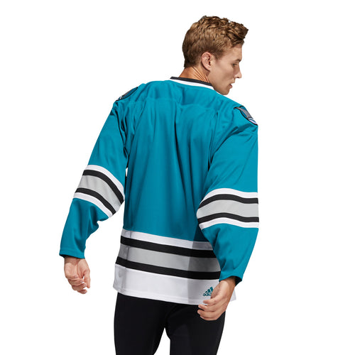 Back view of model wearing the adidas vintage team classics 1991 San Jose Sharks jersey featuring bright teal body. Sleeves and lower hem featuring black. light grey and white stripes
