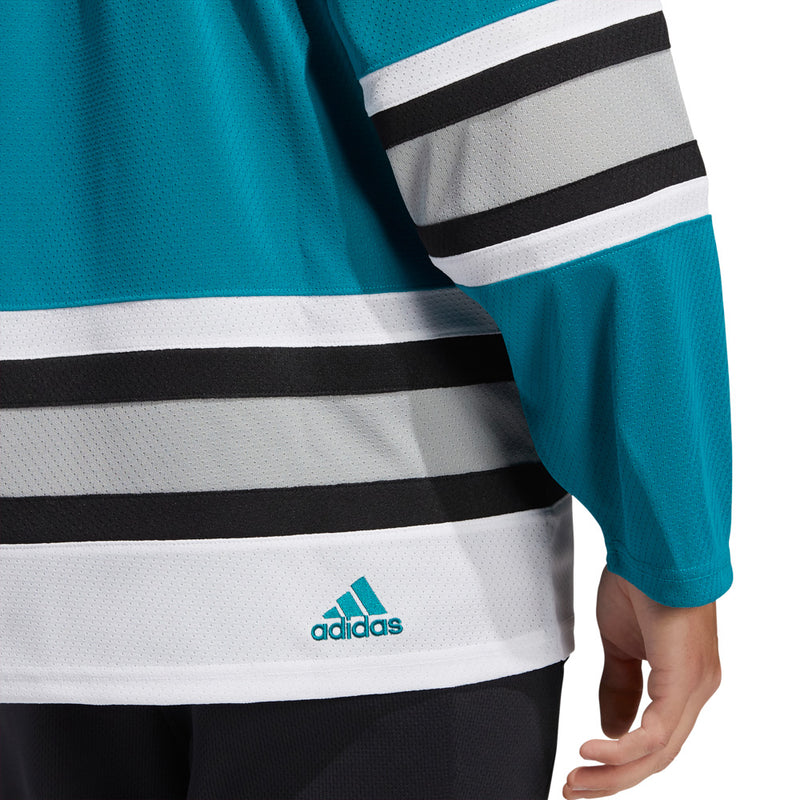 Detail view of adidas vintage team classics 1991 San Jose Sharks jersey, featuring a small embroidered adidas logo at the bottom hem on the right side. 