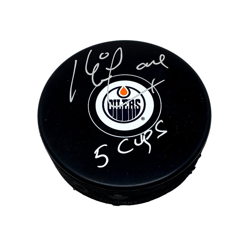Black NHL hockey puck with Edmonton Oilers logo, puck is signed by Kevin Lowe with "5 Cups" inscription. 