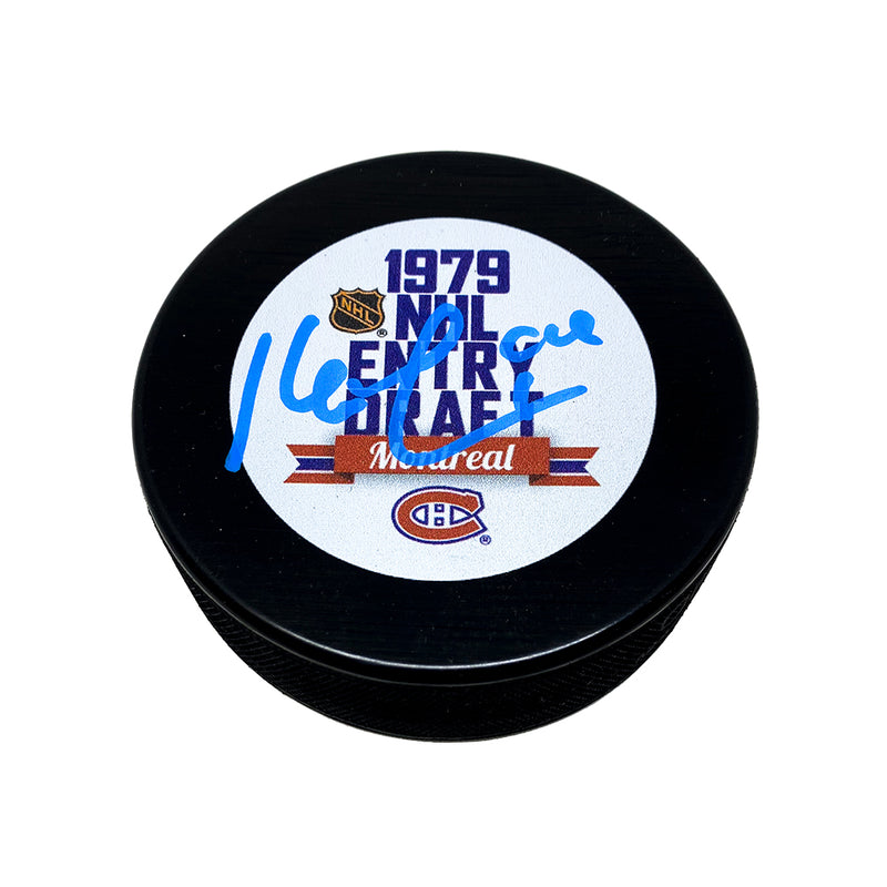 Black hockey puck with 1979 NHL Entry draft Montreal design including Montreal Canadiens and NHL Shield logos. Puck is signed in blue ink by Kevin Lowe