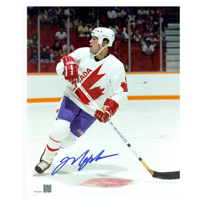 Signed photo of Mark Messier Team Canada skating during a hockey game, wearing white Team Canada maple leaf jersey. He is skating and looking over his right shoulder. Photo is signed in the lower left in blue ink. 