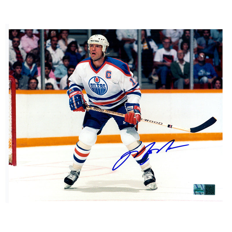 Photo of Edmonton Oiler Mark Messier looking down the rink during an Edmonton Oilers NHL hockey game, wearing white jersey. Photo is signed in the lower right with blue ink. 