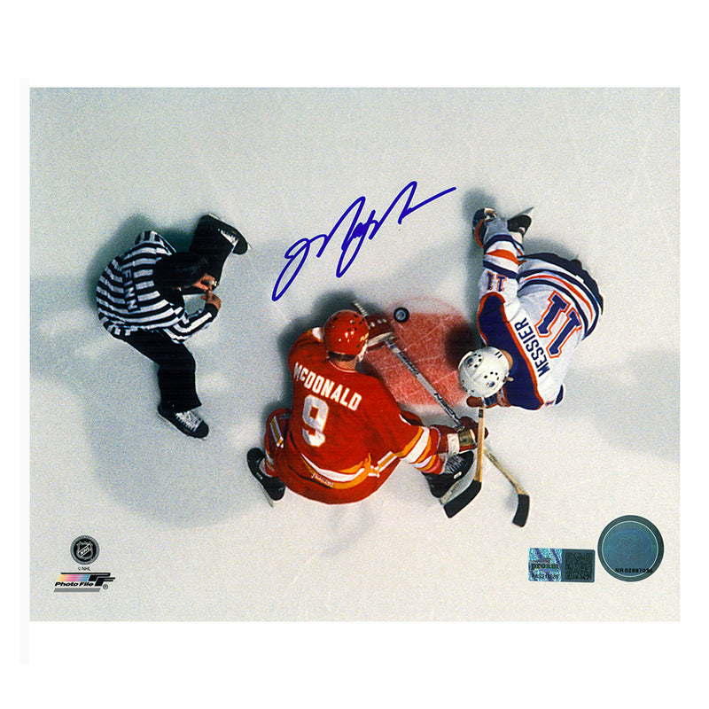 Signed overhead photo of Edmonton Oilers Mark Messier facing off against Calgary Flames Lanny McDonald with referee to the left. Photo is signed by Mark Messier in the upper center in blue ink. 