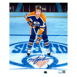 Signed photo of young Mark Messier posed on the ice with stick and puck. He is wearing the Edmonton Oilers royal blue jersey. Photo is signed near the bottom in blue ink. 