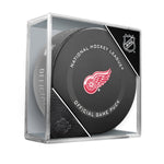 Official 2021-22 Detroit Red Wings NHL game puck; puck design features Red Wings logo at the centre of the front face of puck. Puck is pictured displayed in clear plastic puck cube. 