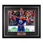 Ryan Smyth celebrating during an Edmonton Oilers NHL hockey game. He is wearing royal blue jersey. Image is signed on the left side in light blue ink. Photo is framed in black, with black mat with orange accent, and team pick and description bar are inset. 