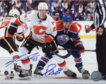 Photo  of Ryan Nugent-Hopkins (Edmonton Oilers) and Sean Monahan (Calgary Flames) during an NHL hockey game. Photo is dual signed by Sean Monahan and Ryan Nugent-Hopkins, signatures are done in blue ink. 