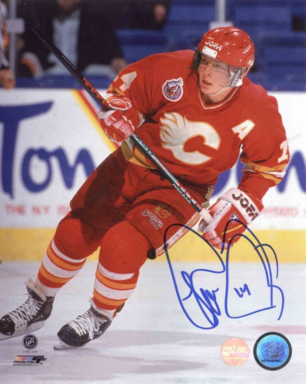 Theo Fleury of the Calgary Flames skating during a Calgary Flames NHL hockey game wearing red jersey with alternate captain's A. photo is signed in blue ink in the bottom right corner 