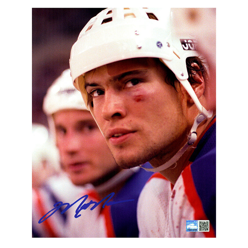 Signed photo of young Edmonton Oilers Mark Messier sitting on the bench during and Oilers game. He is wearing his helmet and has bruising and a cut on his eye and a bandaid over his eyebrow. He is looking slightly above and beyond the camera. The photo is signed in the lower left corner in blue ink. 