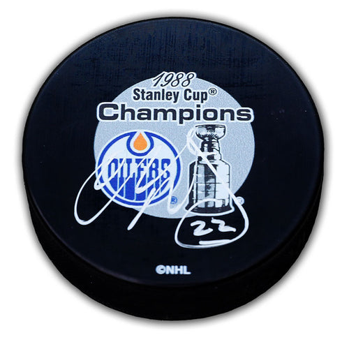 Black NHL hockey puck with Edmonton Oilers 1988 Stanley Cup Champions design, signed by Charlie Huddy