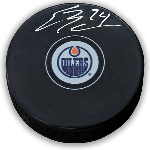 Black NHL hockey puck with Edmonton Oilers logo, signed by Ethan Bear. 