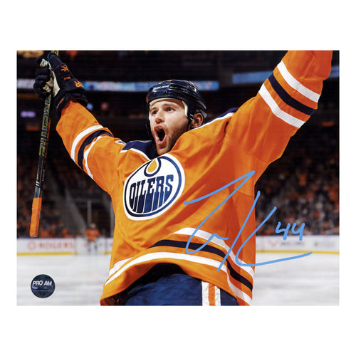 Photo of Edmonton Oiler Zack Kassian wearing orange jersey celebrating during an Oilers NHL hockey game. Photo is signed in light blue ink in the lower right.