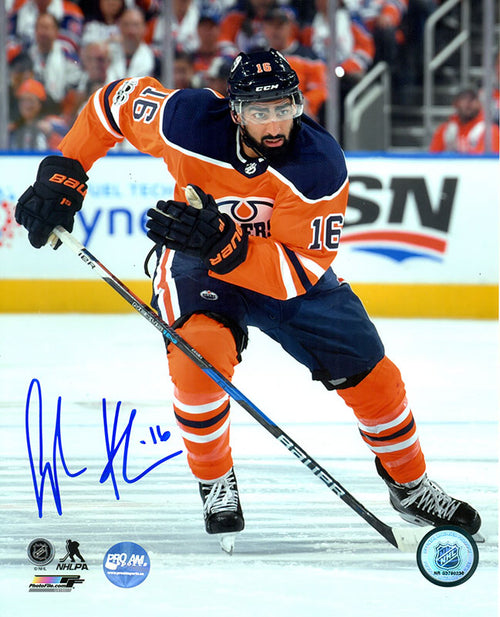 Photo of Jujhar Khaira skating during an Edmonton Oilers NHL hockey game while wearing orange jersey. Photo is singed in blue ink in the bottom left corner. 