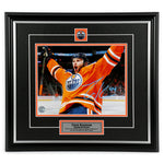 Photo of Edmonton Oiler Zack Kassian wearing orange jersey celebrating during an Oilers NHL hockey game. Photo is signed in light blue ink in the lower right. Photo is shown framed in black frames and mat with orange accents, team pin and description plate are inset. 
