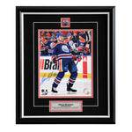 Photo of Oscar Klefbom celebrating during an Edmonton Oilers NHL hockey game. He is wearing the royal blue jersey. Photo is signed in the bottom left corner with blue ink. Photo is shown framed with black framing, black mat with orange accents, and inset team pin and description plate. 