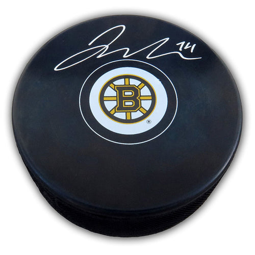 Black NHL hockey puck with Boston Bruins logo, puck has been signed by Jake Debrusk with silver ink. 